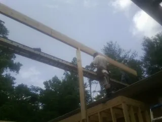 Carpenter setting a ridge beam over a new addition frame — Ice Dam Removal by Roofing Brothers in Bennettsville
