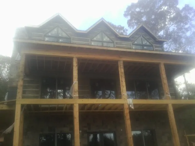 Dormers and porch framing on a large log home under construction — Roof Coating work by our crew in Bennettsville
