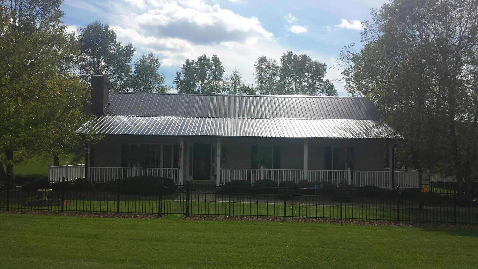 Gray metal roof on a brick ranch with a full width front porch — Gutter Guard Installation work by our crew in Bennettsville
