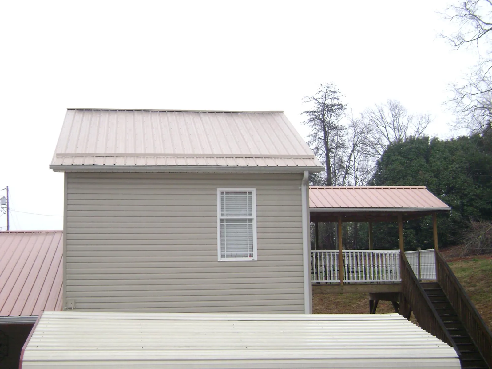 Tan metal roofs on a two story addition and attached porch, from a Roof Replacement job in Bennettsville