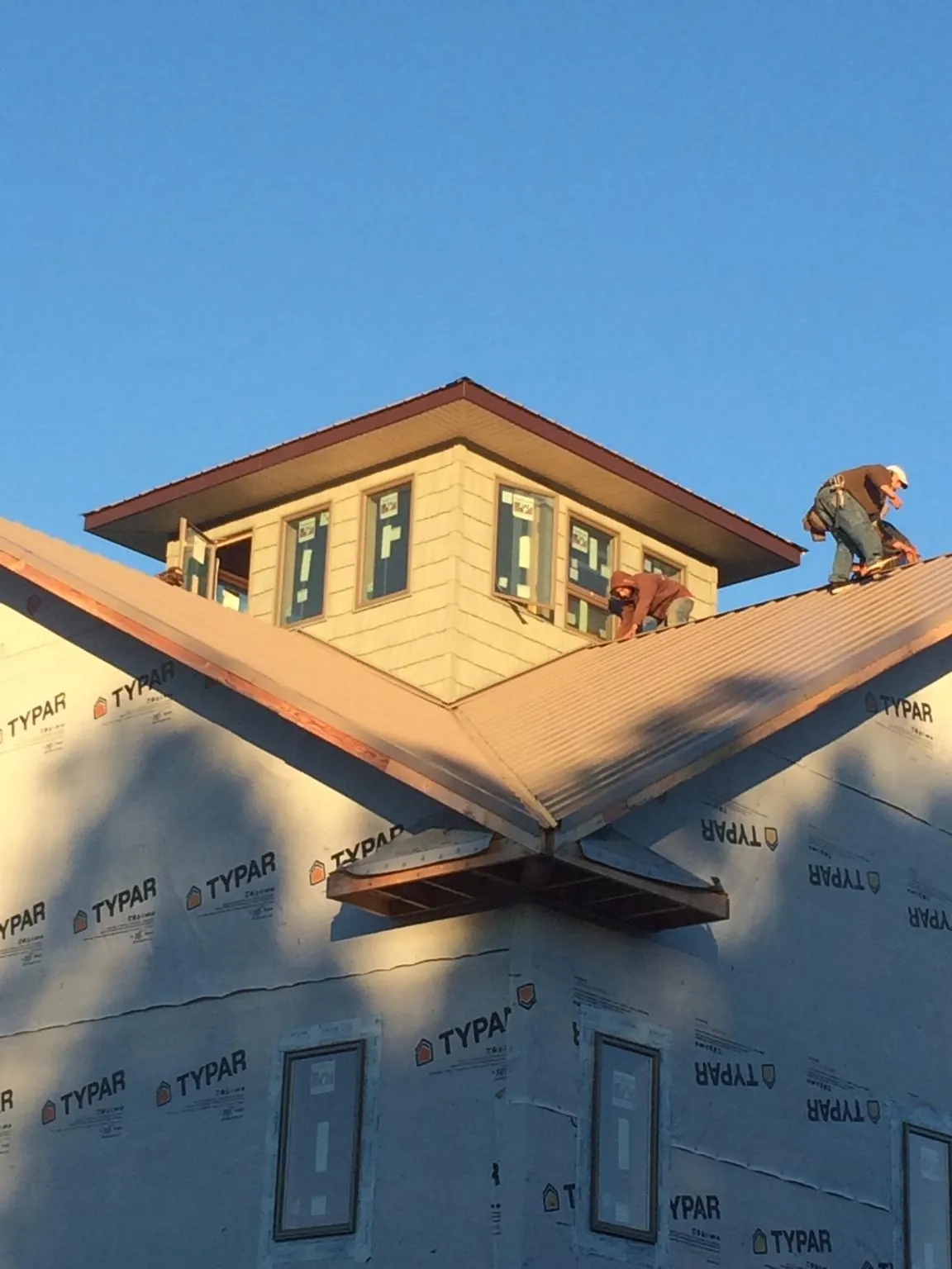 Roofers working around a rooftop cupola on a new metal roof at sunset — Roof Waterproofing in Bennettsville by Roofing Brothers